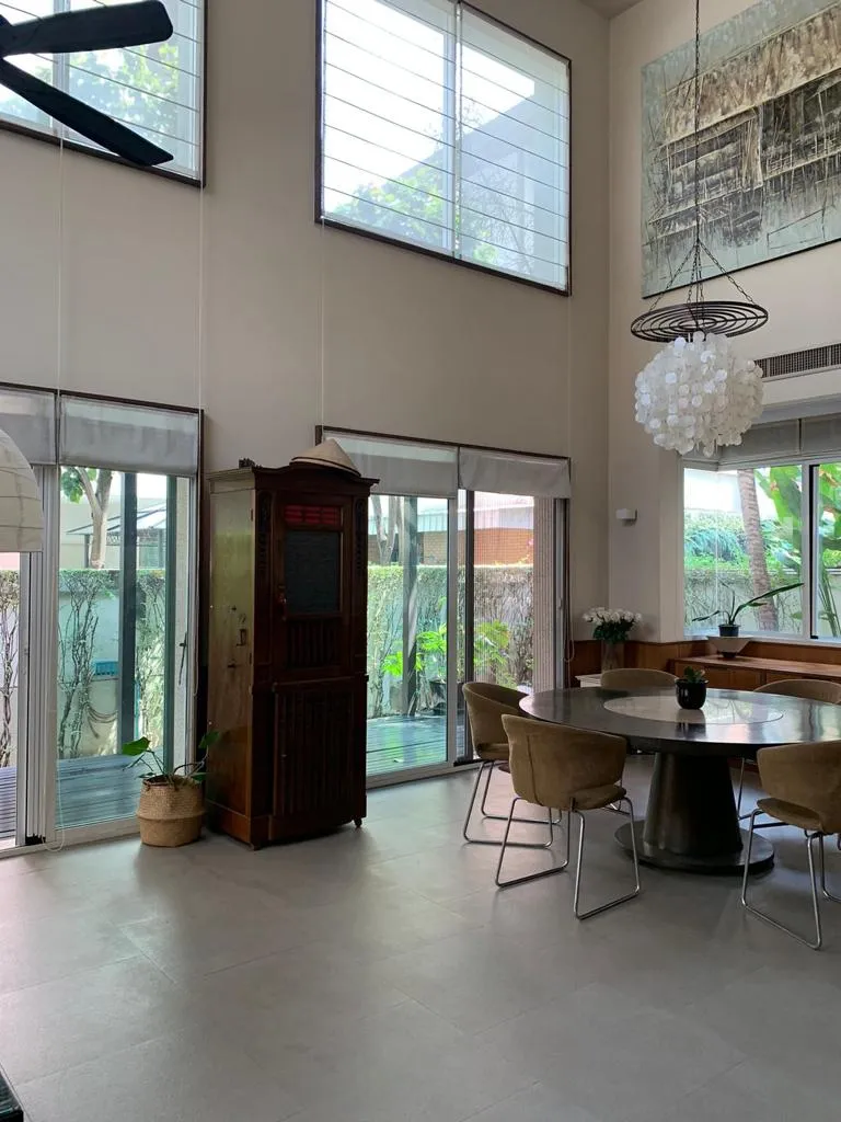 Double-height dining area beside tall garden-facing windows