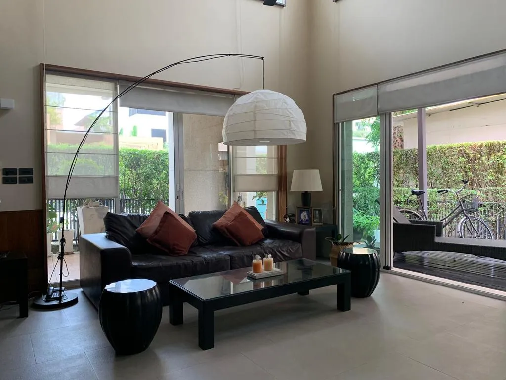 Double-height living room with curved floor lamp and garden-facing windows