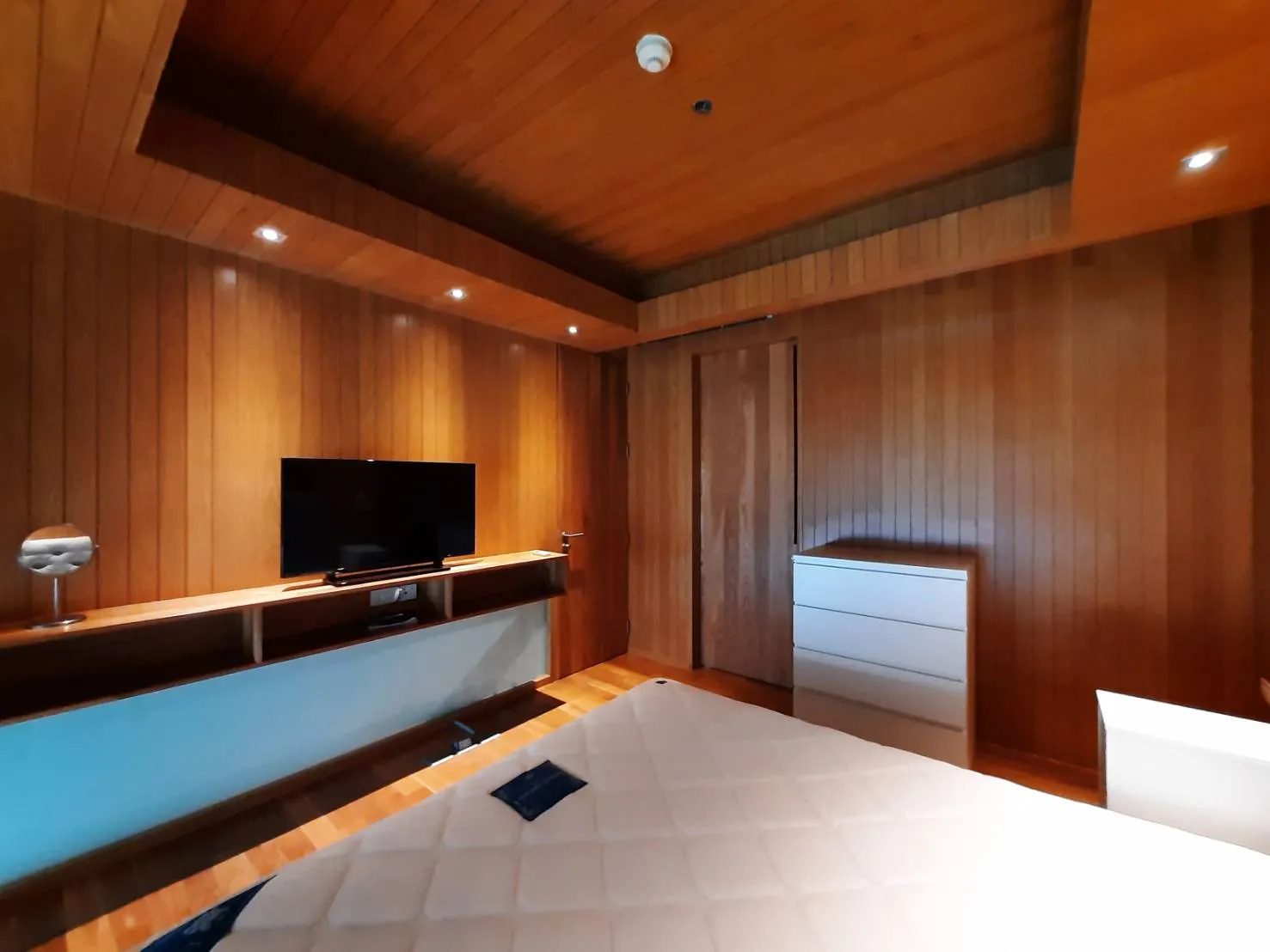 Wood-panelled bedroom with built-in media cabinet